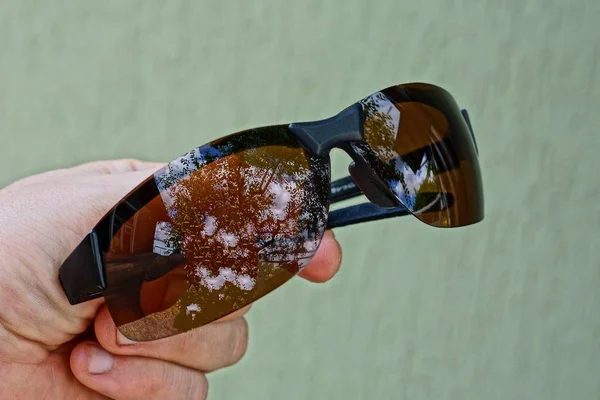 Mano Sostiene Una Gafas Sol Marrones Sobre Fondo Gris —  Fotos de Stock