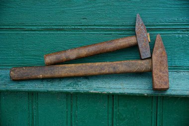 Evin ahşap duvarın yeşil panoları üzerinde iki kahverengi paslı çekiç