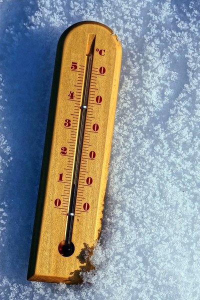 Wooden thermometer in white snow on the street