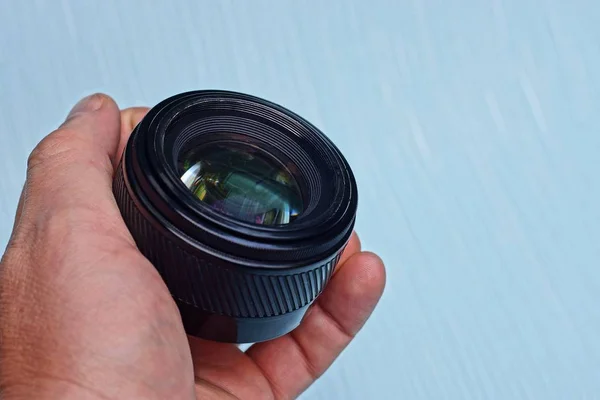 Een Zwarte Open Camera Lens Een Hand Een Blauwe Achtergrond — Stockfoto