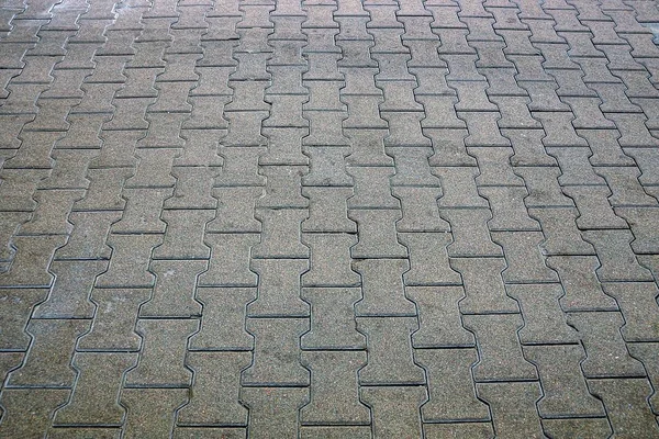 part of the sidewalk on the street with stone gray tiles on the road