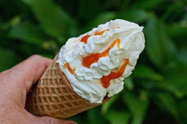 el yeşil bir arka plan üzerinde bir waffle fincan kırmızı reçel ile beyaz dondurma tutar