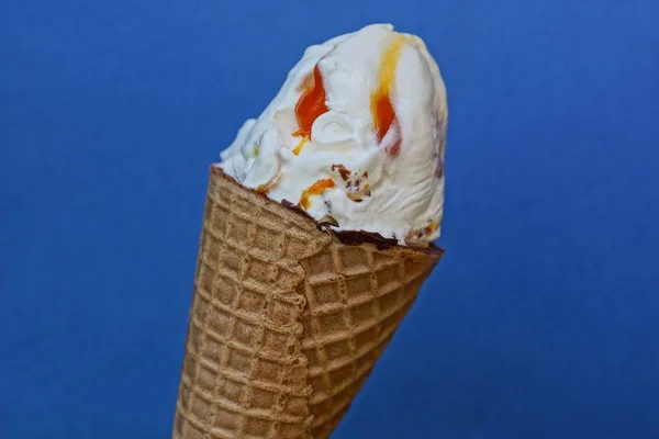 white ice cream with red jam in a brown waffle cup on a blue background