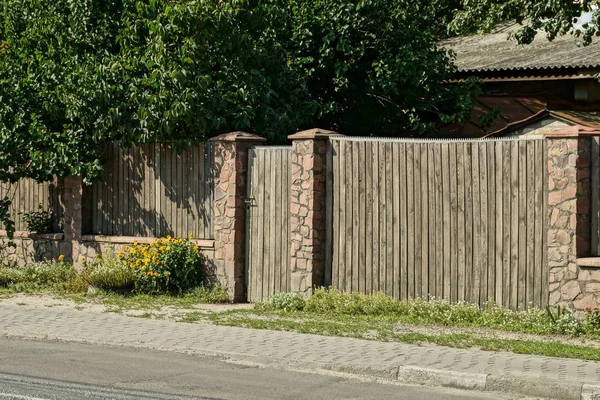 一个灰色棕色的栅栏的一部分 用木板和石头与路边的一个封闭的门 — 图库照片