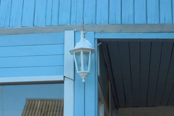一个白色的复古灯笼在窗户边的蓝色木墙上 — 图库照片