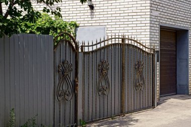 gray iron gate with a pattern and part of a fence in the street clipart