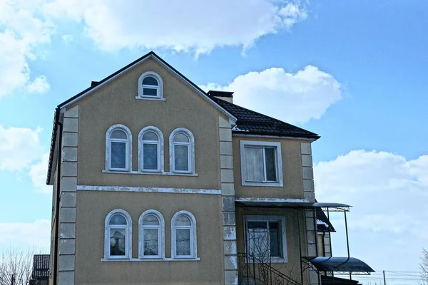 facade of a gray house with two windows against the sky