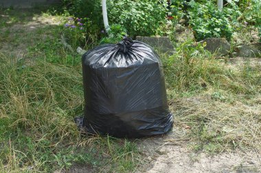  çöp siyah büyük tam çanta yeşil çim dışında duruyor