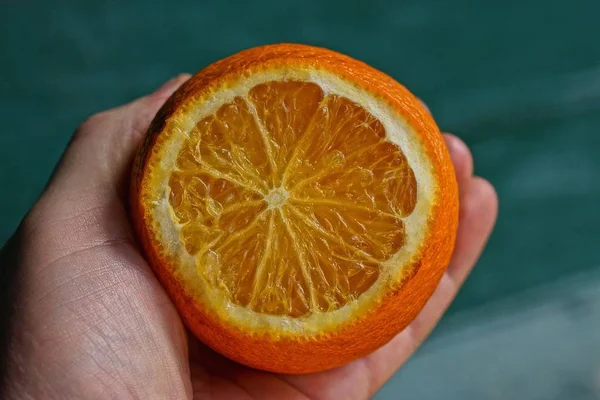 緑の背景に手のひらに熟した新鮮なオレンジのスライス — ストック写真