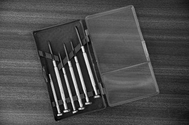 masanın üzerinde açık bir plastik kutu gri metal tornavida seti