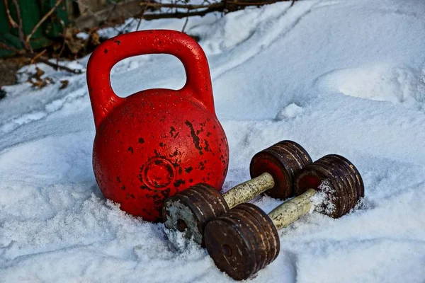 beyaz kar sokakta büyük kırmızı demir kettlebell ve dambıl