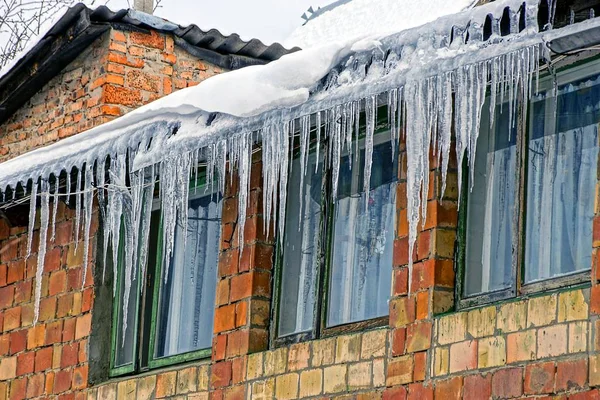 a row of icicles on the roof in the snow over the windows on the brick wall