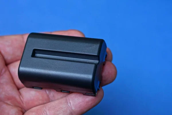 Una Batteria Nera Trova Sulle Dita Uno Sfondo Blu — Foto Stock