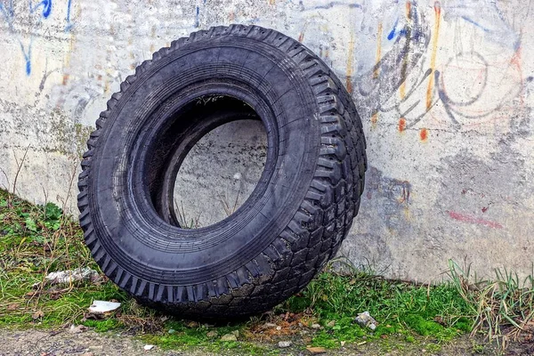 壁の近くの通りに古い黒い車のタイヤ — ストック写真