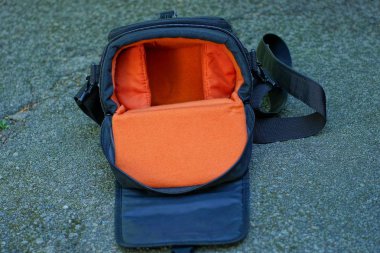 açık boş siyah kırmızı kamera çantası gri asfalt yatıyor