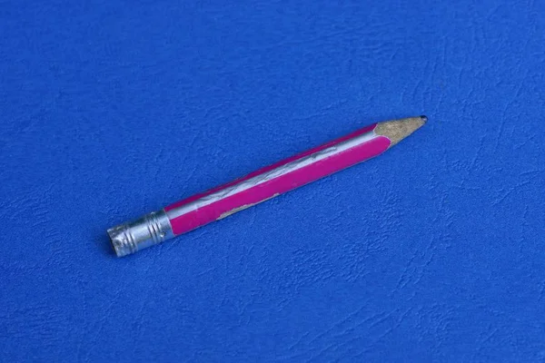 一根红色的旧木铅笔躺在一张蓝色的桌子上 — 图库照片