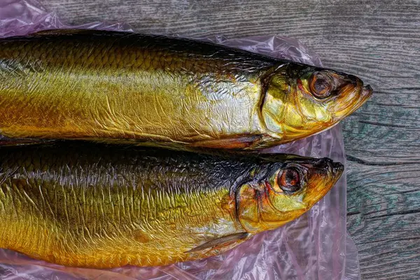 Δύο Καστανά Ψάρια Ρέγγας Βρίσκονται Σελοφάν Και Γκρι Τραπέζι — Φωτογραφία Αρχείου