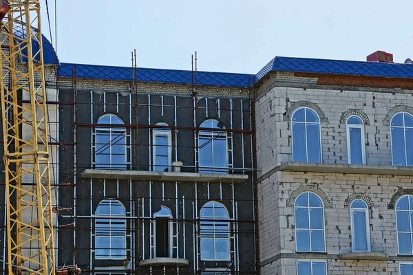 repair of a large black gray house with windows against a blue sky