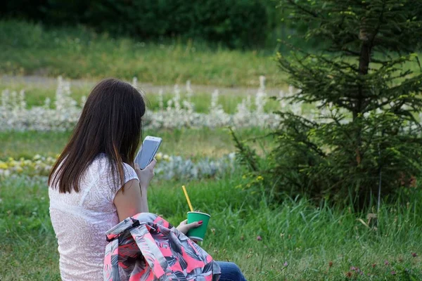 Bir Kız Elinde Bir Cep Telefonu Kahve Ile Parkta Oturuyor — Stok fotoğraf