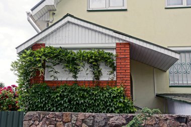 Bir çit arkasında bitkiler ile büyümüş özel bir binanın cephe