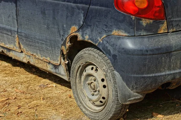  paslı bir kanat ve gri bir tekerlek ile eski mavi araba