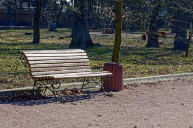  kahverengi ahşap bank ve bir vazo yeşil çim ve ağaçlar arasında parkta bir sokakta duruyor