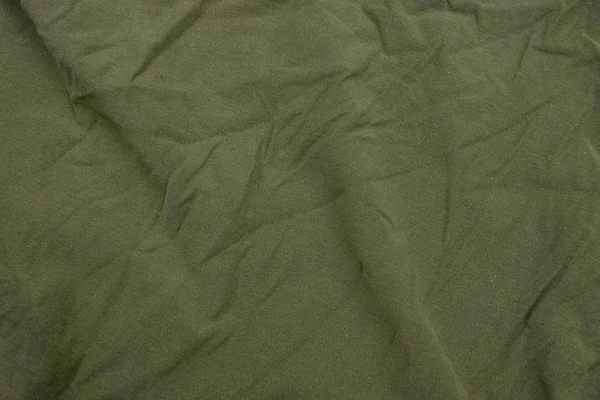 green fabric texture from a piece of crumpled matter on clothes
