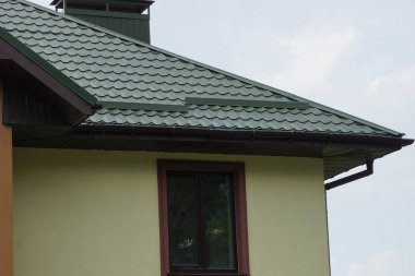 bir pencere ile büyük bir özel evin tavan çatısında yeşil kiremit