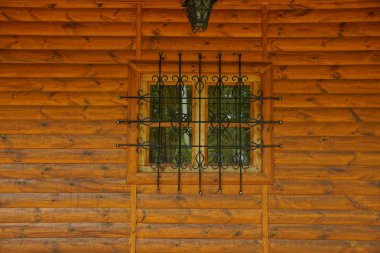 kahverengi ahşap kütük duvarüzerinde siyah demir çubuklar arkasında bir pencere