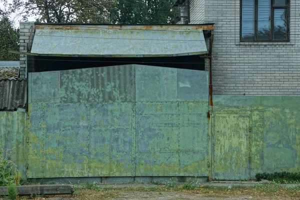 绿色金属门和一条乡村街道上的栅栏碎片 — 图库照片