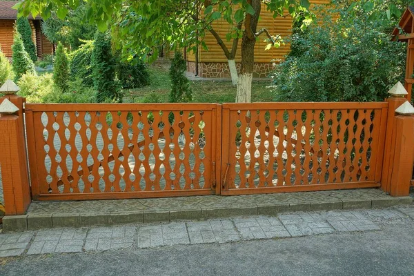 sokakta gri bir kaldırım üzerinde panoları yapılmış dekoratif kahverengi kapı
