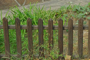 Uzun otların arasında küçük kahverengi ahşap çitler.