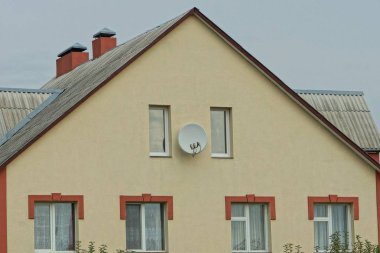 Kahverengi kiremit çatılı ve gökyüzüne bakan pencereli özel bir evin parçası.