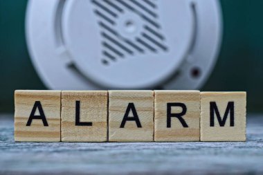 Tahta harflerden yapılmış kelime alarmı ve plastik bir anonsör. 