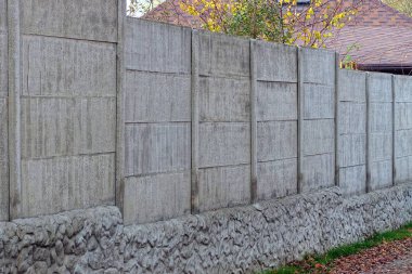 part of a gray concrete fence on a rural street in the grass