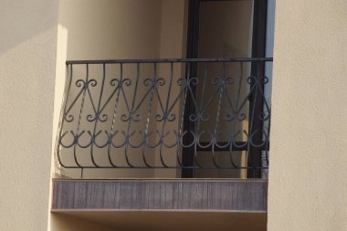 Kahverengi bir duvarda demirden yapılmış siyah, açık bir balkon.