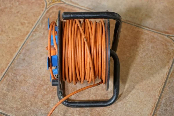 Tekercs Narancssárga Hosszabbító Kábel Van Egy Barna Csempe Szobában — Stock Fotó