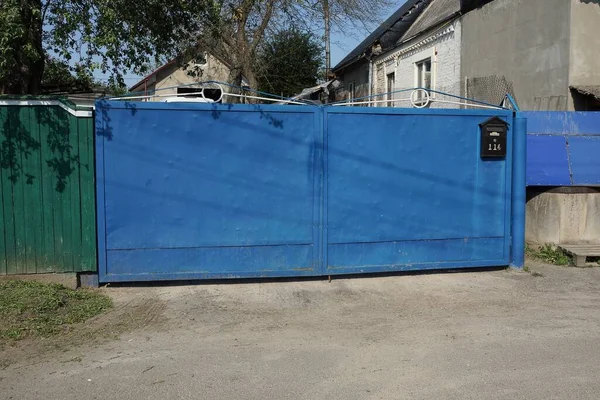 一个蓝色的乡村金属门和街道上的部分围栏 — 图库照片