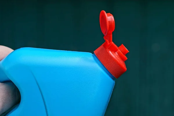 Рука Тримає Синю Пластикову Пляшку Відкритою Червоною Пробкою Зеленому Фоні — стокове фото