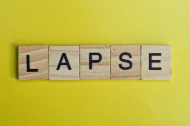 Gri renkli küçük tahta harfler sarı bir masanın üzerinde uzanıyor.