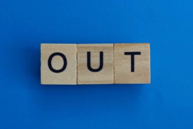 text on gray word out in small wooden letters with black font on a blue background