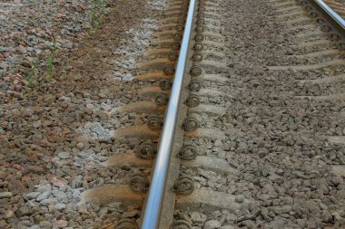 long iron rail with concrete sleepers in gray rubble on the railway
