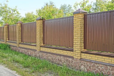 # Çitten yapılmış kahverengi bir duvar ve yeşil çimlerin üzerinde tuğlalar #