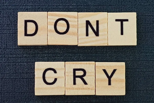 phrase on dont cry from gray wooden letters on a black background