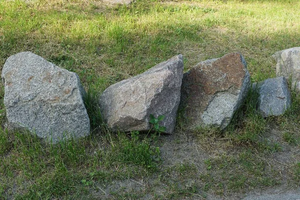 Rząd Dużych Szarych Kamieni Leży Zielonej Trawie Ulicy — Zdjęcie stockowe