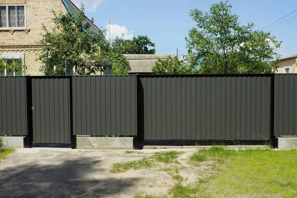 灰色の閉じた金属製の門と緑の芝生の上の通りのフェンスの一部のドア — ストック写真