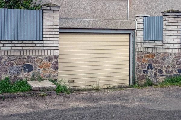 Gri Beton Duvardaki Kahverengi Garaj Kapısı Asfalt Yolun Yanındaki Taş — Stok fotoğraf