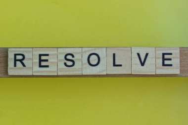 sarı arkaplanda siyah yazı tipi olan küçük kare tahta harflerle çözünür.