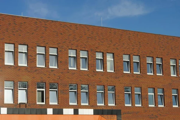 青い空に向かって窓のある建物の大きな茶色のレンガの壁 — ストック写真