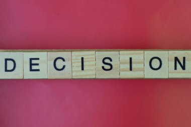 Kelime kararını kırmızı masadaki siyah yazı tipli gri tahta harflerden yaz.